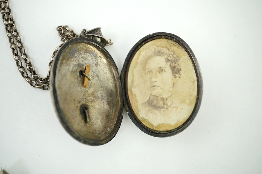 An oval engraved white metal enclosed locket and chain and five assorted white metal brooches. Condition - fair